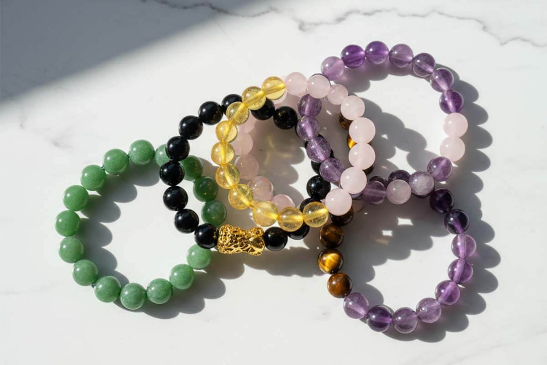 Handcrafted feng shui bracelets featuring natural gemstones  and traditional symbols arranged on marble surface