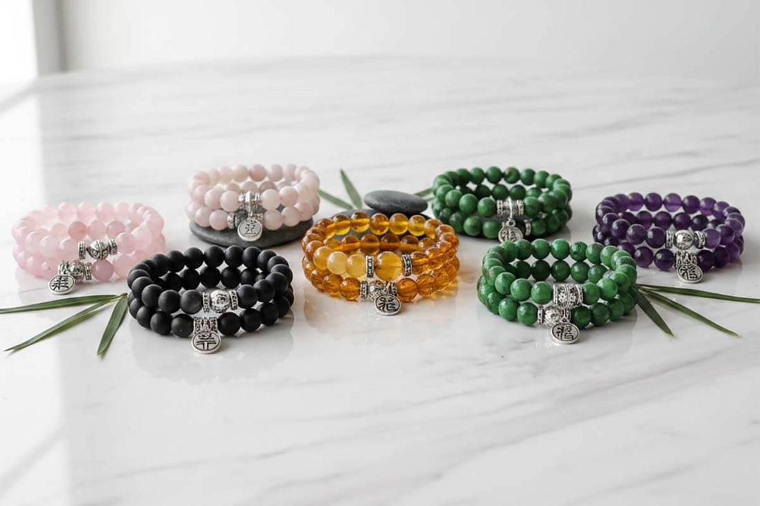 Collection of handcrafted feng shui bracelets featuring natural gemstones in traditional five elements colors including black obsidian, jade, and citrine displayed on a marble surface