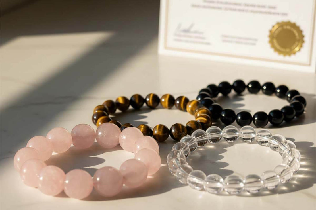 Collection of genuine natural crystal bracelets including rose quartz, tiger eye, and obsidian with certificate of authenticity on marble surface