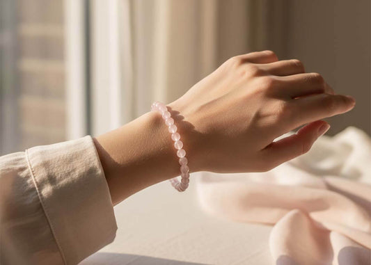 Woman wearing natural rose quartz bracelet on wrist in soft natural light showcasing delicate pink crystal beads