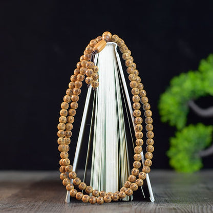 Wooden mala beads displayed in a coiled shape on a rustic wooden surface