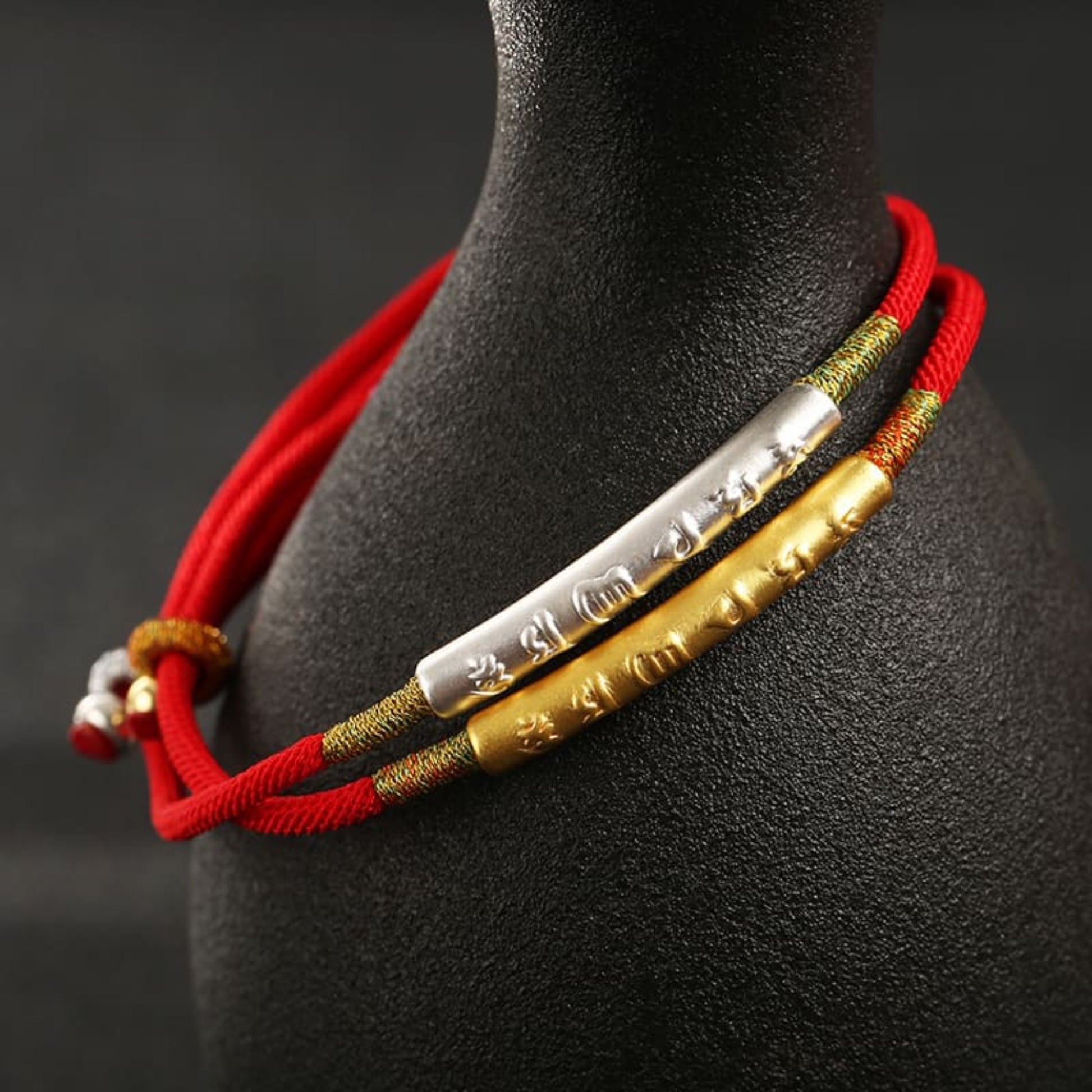 TrueZenBeads Tibetan red string bracelet featuring gold or silver mantra engraving, angled view highlighting beads and string details