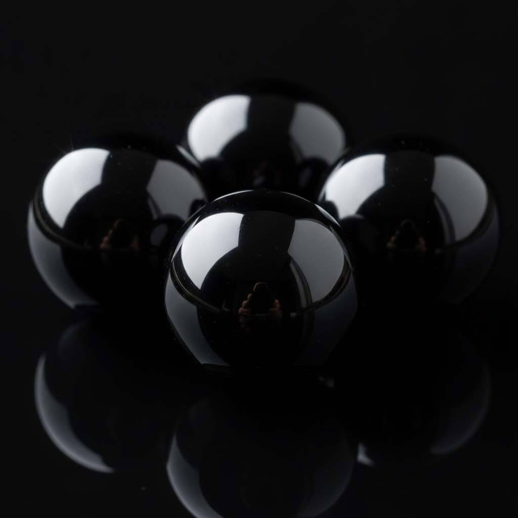 Extreme close-up of polished black obsidian beads showing mirror-like reflective surface - premium volcanic glass crystal quality