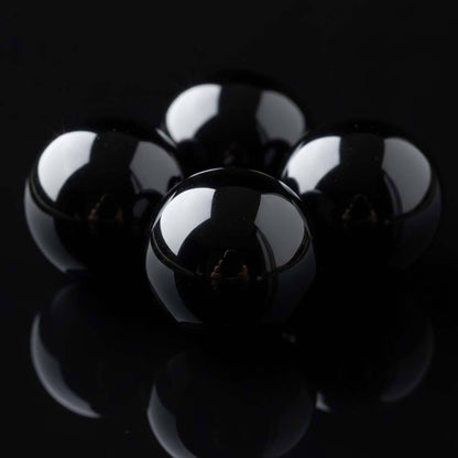 Extreme close-up of polished black obsidian beads showing mirror-like reflective surface - premium volcanic glass crystal quality