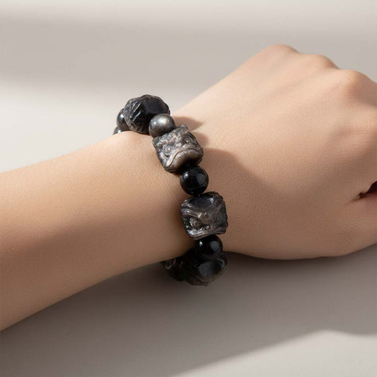 Person wearing black obsidian protection bracelet with silver lion charms on wrist