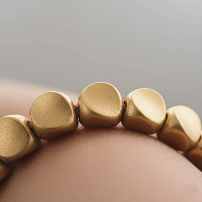 Close-up of hand-hammered gold plated copper beads showing irregular pebble shapes and polished finish