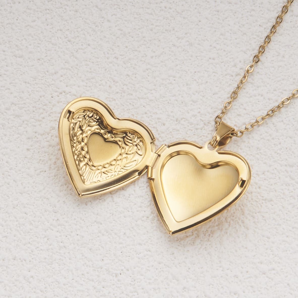 Heart photo locket opened showing two interior compartments and frame spaces for photos with artisan hinged design.
