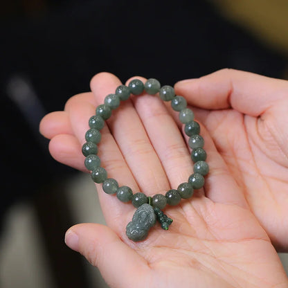 Person wearing natural jade Pixiu bracelet on wrist showing adjustable elastic fit and green beads