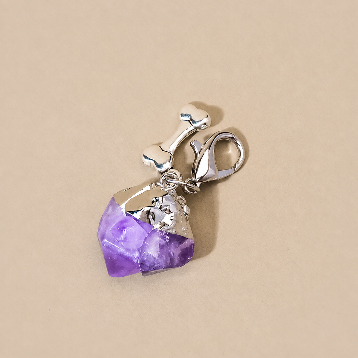 Close-up of purple amethyst crystal point pet charm with silver bone detail