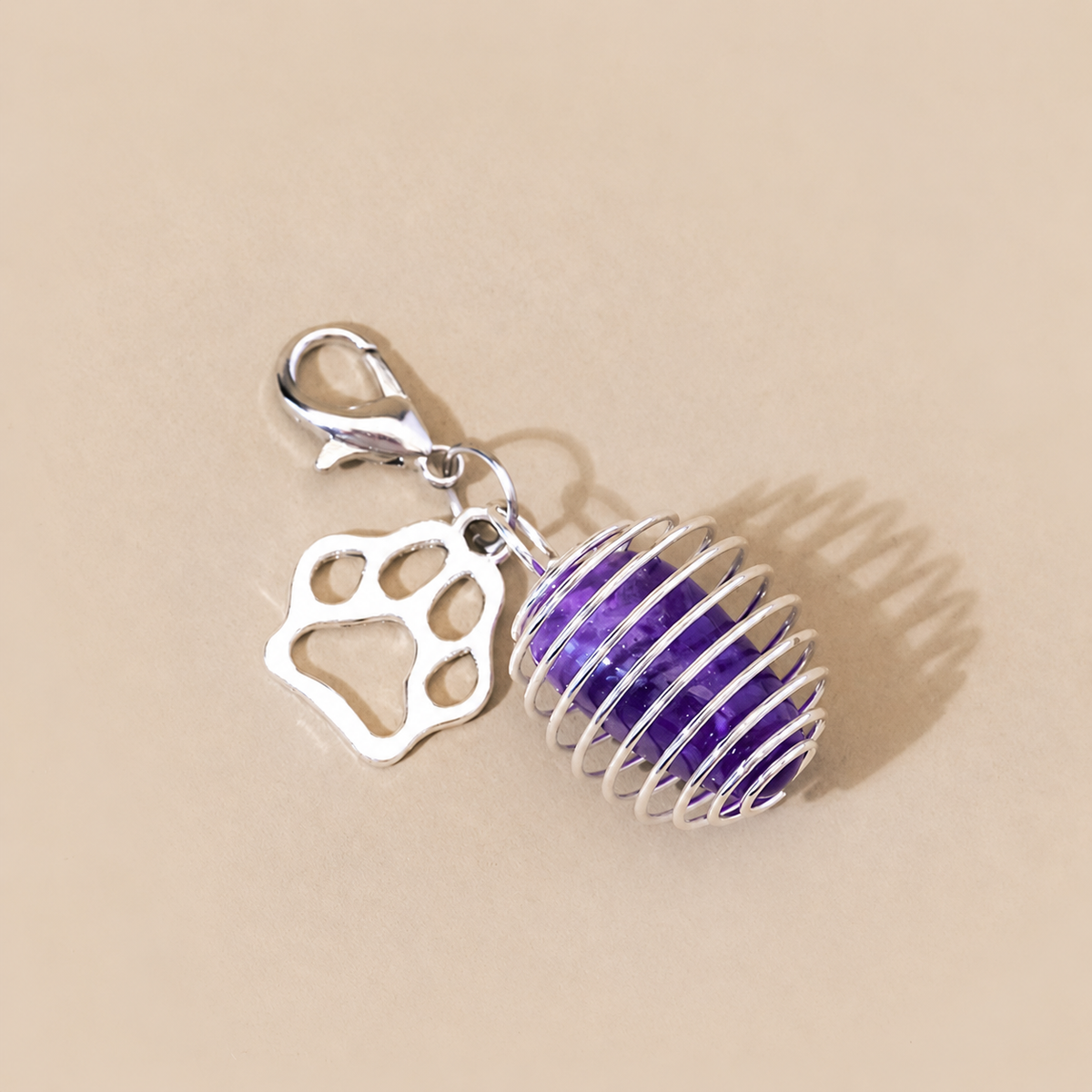 Close-up of tumbled amethyst pet charm with silver paw detail