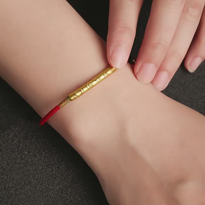 Close-up of red string bracelet handcrafted with Om Mani Padme Hum mantra in silver detail