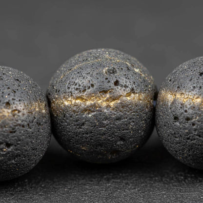 Extreme close-up of raw gold obsidian beads showing natural matte surface texture and subtle golden sheen - unpolished authentic volcanic stone