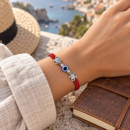 Red string turtle evil eye bracelet worn in an everyday travel lifestyle scene