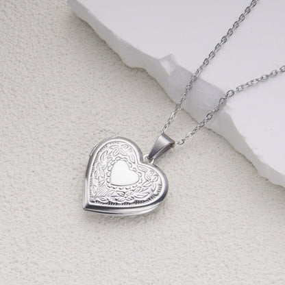 Silver heart locket necklace detail on a light stone background