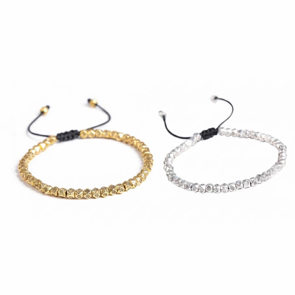 Tibetan mantra faceted copper beads bracelet showing gold tone on left and 
silver tone on right with hand-engraved Buddhist symbols and black cord