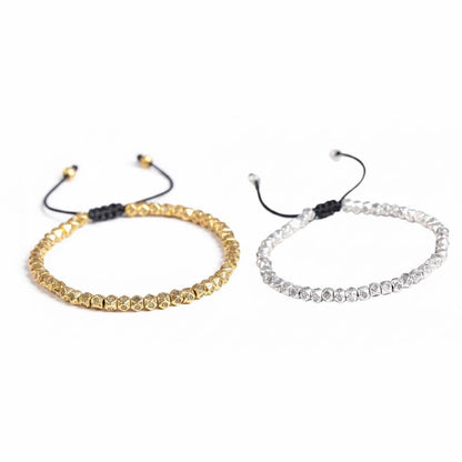 Tibetan mantra faceted copper beads bracelet showing gold tone on left and 
silver tone on right with hand-engraved Buddhist symbols and black cord