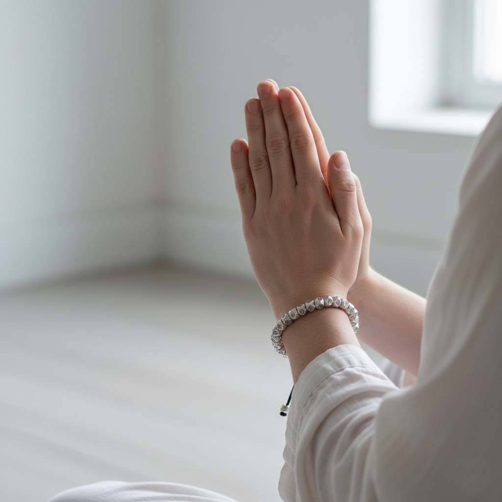 Person wearing silver tone Tibetan mantra bracelet on wrist during meditation practice showing adjustable fit