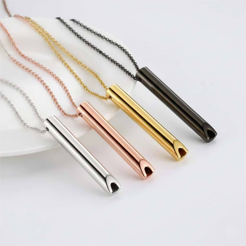 Collection of stainless steel whistle pendants in four finishes: polished steel, rose gold, gold tone, and matte black featuring 60mm cylindrical designs