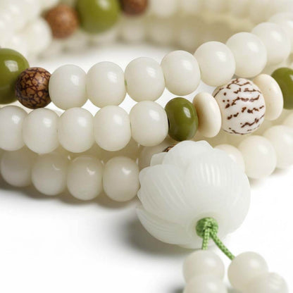 Close-up of white Bodhi beads showing natural texture with carved lotus pendant and jade accent beads